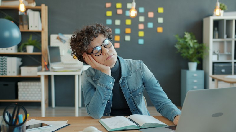 Tired person resting head on hand representing Armodafinil withdrawal effects