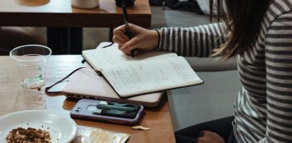 Woman writing in a notebook at a cafe representing coping with anxiety and depression using Fluoxetine