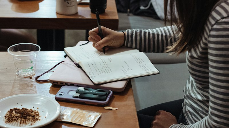 Woman writing in a notebook at a cafe representing coping with anxiety and depression using Fluoxetine
