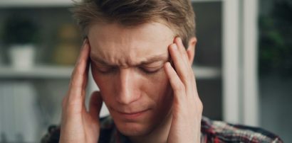 Man holding his temples with eyes closed representing migraine relief with Sumatriptan