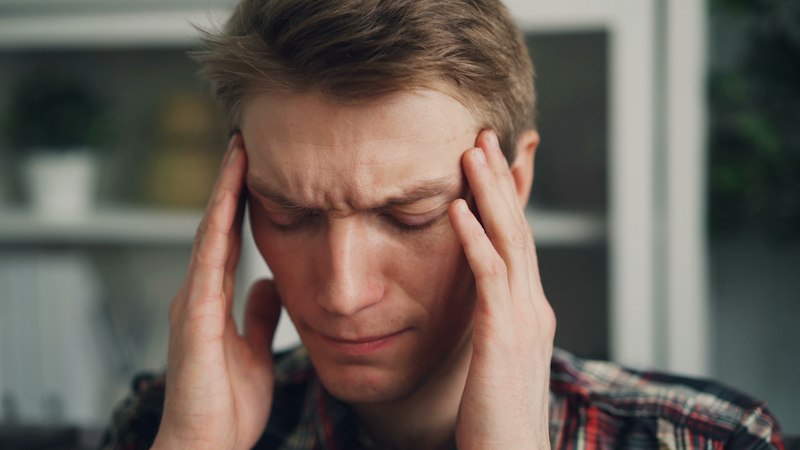 Man holding his temples with eyes closed representing migraine relief with Sumatriptan